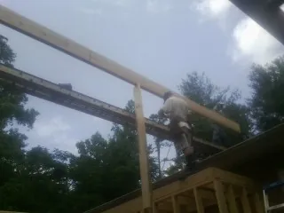 Carpenter setting a ridge beam over a new addition frame — Ice Dam Removal by Roofing Brothers in Malinta