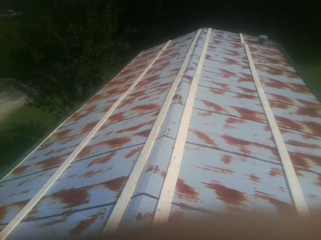 Rusted metal roof panels with new wood purlins before replacement — Storm Damage Roof Repair in Malinta by Roofing Brothers