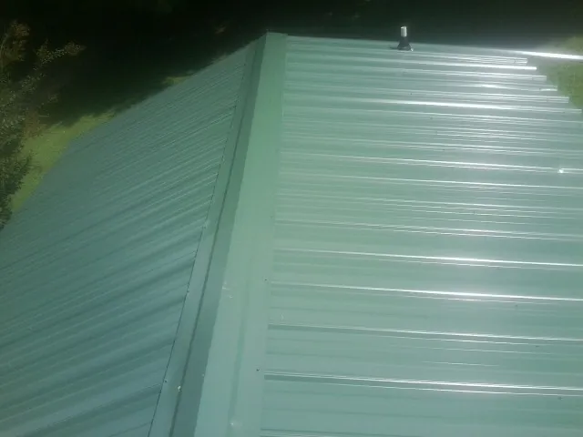 New green metal panels meeting at the ridge of a roof — Flat Roof Repair work by our crew in Malinta