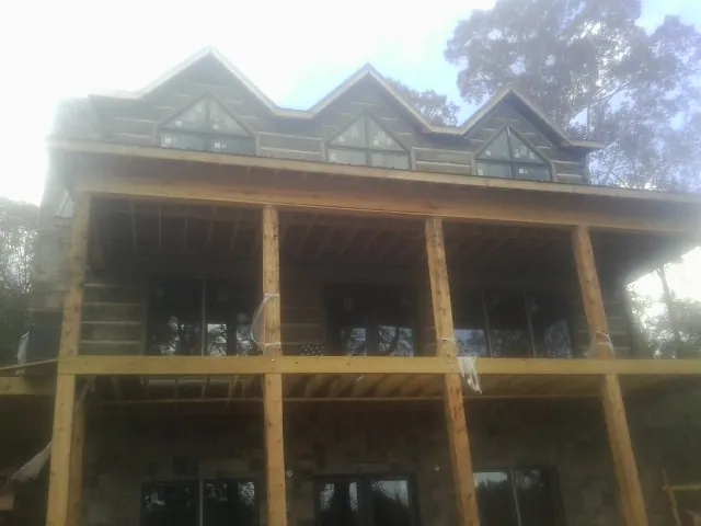 Dormers and porch framing on a large log home under construction — Roof Coating work by our crew in Malinta