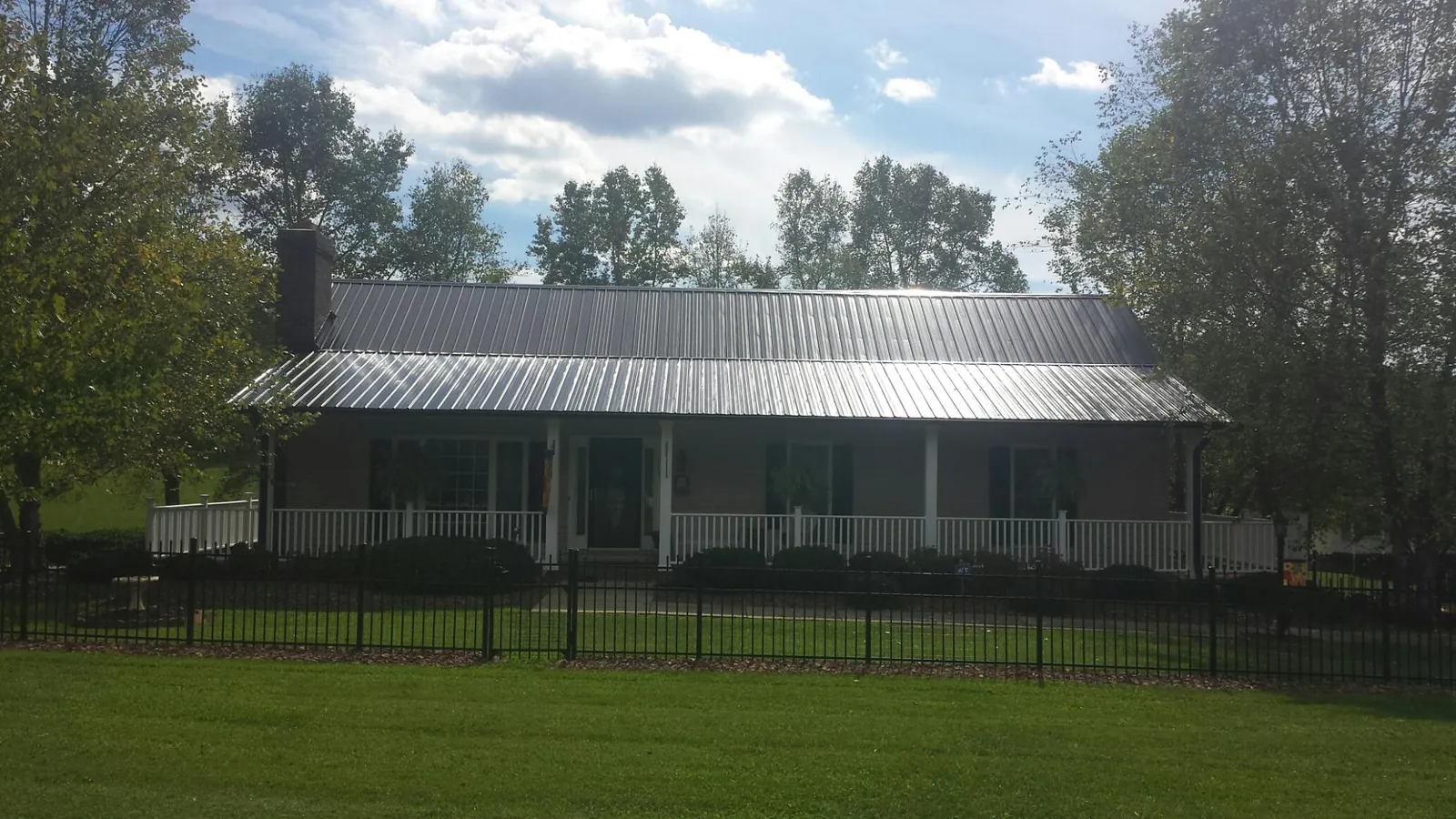 Gray metal roof on a brick ranch with a full width front porch — Gutter Guard Installation work by our crew in Malinta