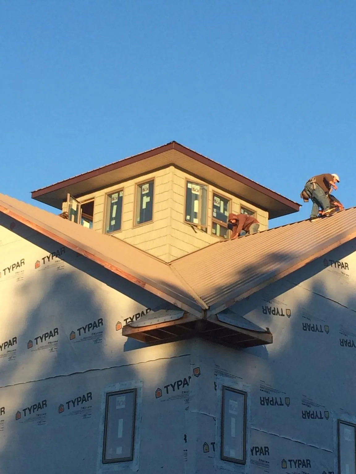 Roofers working around a rooftop cupola on a new metal roof at sunset — Roof Waterproofing in Malinta by Roofing Brothers